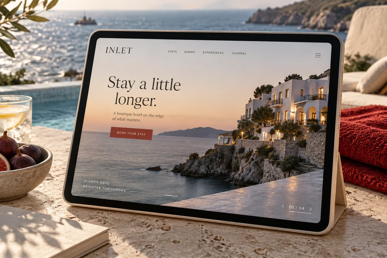 A boutique hotel website concept displayed on a tablet beside a sea-view pool