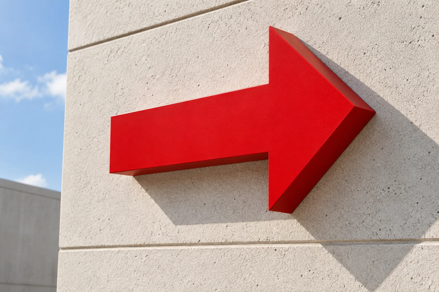 A single scarlet directional arrow on a bright architectural wall